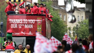 Arsenal players wave to fans from the top deck of an open-topped bus during the Arsenal victory parade in London on May 31, 2015, following their win in the English FA Cup final football match on May 30, 2014 against Aston Villa. AFP PHOTO / LEON NEAL