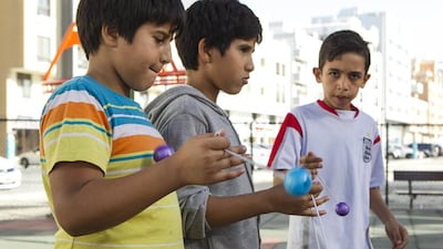 From left, Noor Ahmed, 10, Mahdi Ahmed, 12, and Ibrahim Arikat, 11, all from Jordan, play with their clackers in an Abu Dhabi park, oblivious to the annoying noise they make. Mona Al Marzooqi / The National