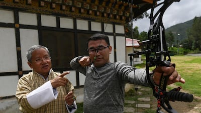 Kinzang Dorji, left, president of the Bhutan Indigenous Games and Sports Association, explains how a compound bow works. AFP