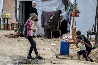 Children move a container up a slope at a camp housing displaced Palestinians in Rafah in the southern Gaza Strip. AFP
