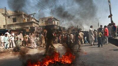 A Pakistani policeman walks past burning tyres set alight by protesters in Karachi today.