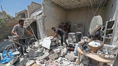 Abu Abdullah (centre), a Syrian displaced from the town of Khan Sheikhoun in Idlib province, inspects his belongings at his now-destroyed home upon returning during a temporary truce. Omar Haj Kadour / AFP