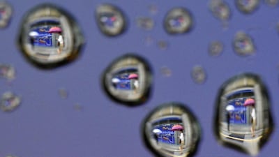 An image rotated 180 degrees shows raindrops on a car window reflecting pedestrians walking past a stock market indicator board in Tokyo, Japan. Franck Robichon / EPA