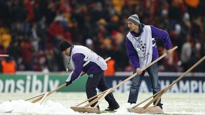 Workers clean the pitch from hail and snow during the Uefa Champions League Group B match between Galatasaray and Juventus in Istanbul, Turkey last night. The match was abandoned in the 34th minute due to heavy snowfall. Tolga Bozoglu / EPA