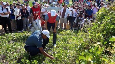 Tiger Woods, left, checks the lie of his golf ball, assisted by Martin Kaymer on the 5th hole during the second round of the Abu Dhabi HSBC Golf Championship on Friday. Woods, along with world No 1 Rory McIlroy, missed the cut.