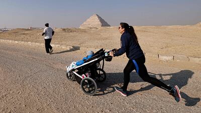 A runner pushes a stroller as she takes part in race. AFP