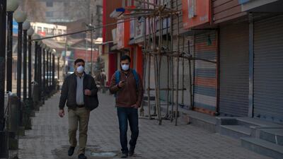 Kashmiri men wearing protective masks walk past closed shops as restrictions continued on the movement of people in Srinagar, Indian controlled Kashmir. AP Photo