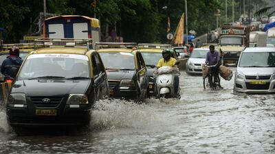 Indian commuters drive along a flooded road in Mumbai. Punit Paranjpe / AFP
