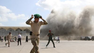A security personnel member reacts as dust rises after explosions hit Aden airport, upon the arrival of the newly-formed Yemeni government in Aden, Yemen. REUTERS