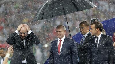 Russian President Vladimir Putin stands underneath an umbrella watched by French President Emmanuel Macron after the final match between France and Croatia at the 2018 soccer World Cup in the Luzhniki Stadium in Moscow. Matthias Schrader / AP Photo