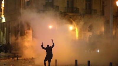 A Lebanese protester gestures at riot police guarding a road leading to parliament in central Beirut on January 19, 2020 amid ongoing anti-government demonstrations. / AFP / PATRICK BAZ