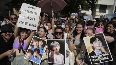 Fans hold up photos and posters for Jin.
