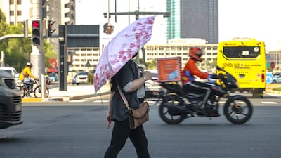 A pedestrian attempts to keep cool on a hot summer's day in downtown Abu Dhabi. Victor Besa / The National