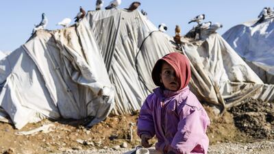 A child stands next to a pail of water outside a tent at Abu Al-Khashab camp in Deir Ezzor, Syria. AFP