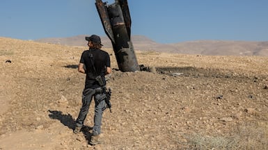 An Israeli settler approaches part of an Iranian missile that landed in the occupied West Bank, during the latest exchange of strikes. Reuters