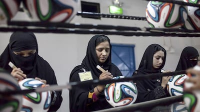 Employees conduct a final check to fix any cavities in the seams of balls. Sara Farid / Reuters