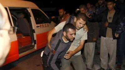 A Palestinian helps a wounded man to the al-Aqsa hospital in Der el Balah, Gaza.