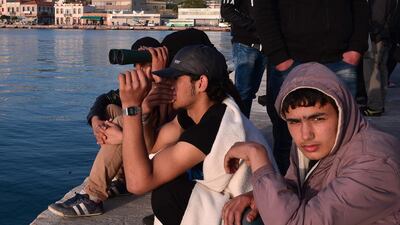 Migrants who camp out at the port of Chios watch the migrants embarking a Turkish catamaran taking the first group of migrants to be sent back to Turkey. Louisa Gouliamaki / AFP