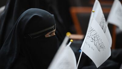 Veiled students hold Taliban flags as they listen to a speaker before the women marched in support of the Taliban. AFP