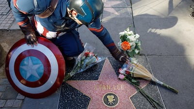 A Captain America impersonator touches the flowers covering the Walk of Fame star in memory of Stan Lee. EPA