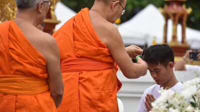 Buddhist monks cut the hair of the rescued coach Ekkapol Chantawong. AFP