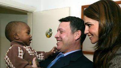 King Abdullah II and Queen Rania of Jordan playing with a little boy on a visit to the Hussein Foundation for orphans in Amman in November 2003. AFP