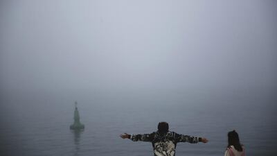 Chinese tourists Zishun Wei, left, and Siyu Zheng, right, enjoy the cool morning as heavy fog engulfs the Palm Jumeirah. Jon Gambrell / AP Photo