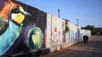 People walk along the concrete barrier forming Israel's northern border with Lebanon near the village of Shtula. AFP