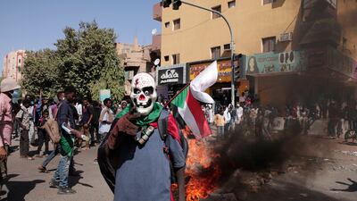 A masked demonstrator stands in front of burning tyres during a protest on Tuesday against the military takeover in Sudan. AP