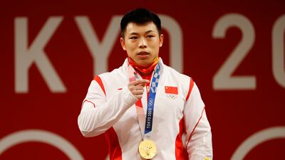 Gold medalitst Lijun Chen of China celebrates on the podium after the men's 67kg weightlifting event.