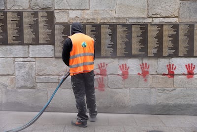 A city employee cleans red-hand graffiti from the 'Wall of the Righteous' outside the Shoah memorial in Paris, in May 2024. AFP