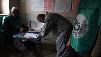 This photo taken on April 14, 2018 shows Afghan employees of the Independent Election Commission (IEC) registering a resident at a voter registration center for the upcoming parliamentary and district council elections in Kabul. Wakil Kohsar / AFP