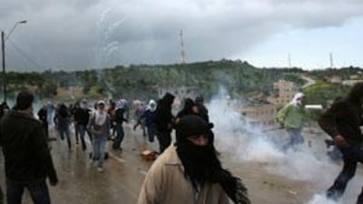 Arab Israelis run for cover as Israeli riot police fire tear gas in the northern town of Umm El-Fahm.