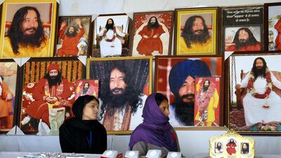 Indian followers of deceased guru Ashutosh Maharaj sit in front of posters bearing his image at his ashram on December 14, 2014. AFP