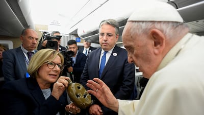 Pope Francis blesses a damaged water canteen belonging to a wounded Ukrainian soldier, on board his flight to Mongolia. Reuters