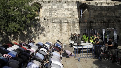 Israeli border police officers stand guard as Muslim men pray outside the Al Aqsa mosque compound in Jerusalem on Sunday. AP / Mahmoud Illean