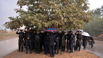 Pakistani policemen crouch under a tree in Islamabad to escape the rain. Aamir Qureshi / AFP Photo