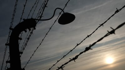 Barbed wire and a floodlight stand silhouetted against the sky at the former Auschwitz-Birkenau German concentration camp. Getty
