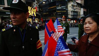 A woman holding North Korean and US flags stands near the Metropole Hotel. Reuters