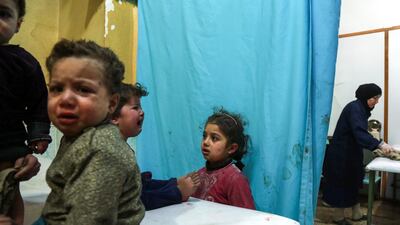 A Syrian girl looks at another crying child sitting on a hospital bed in a make-shift clinic in the rebel-held town of Douma, in the besieged Eastern Ghouta region on the outskirts of the capital Damascus, after they arrived to receive medical attention following reported regime bombardment on the area. Hamza Al-Ajweh / AFP