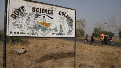 People walk past a sign for the Government Science College, in Kagara, where gunmen kidnapped 42 people on February 17. On February 23, the abducted pupils, staff and family members were still missing. AFP
