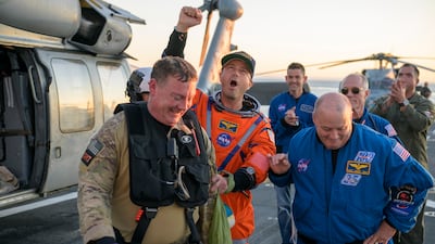 Nasa astronaut and Artemis II commander Reid Wiseman, centre, is assisted off the flight deck of the amphibious transport ship USS John P Murtha after the crew's return to Earth. EPA