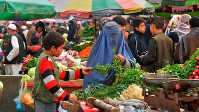 An Afghan burqa clad woman buys vegetable at a market in Kabul on December 9, 2019. AFP