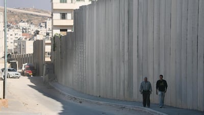 People walk through the separation barrier which runs through Alram neighbourhood of Jerusalem Andrew Parsons / The National