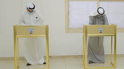 People ware wearing protective masks cast their votes at a polling station in Kuwait City. EPA