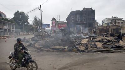 A man rides a motorcycle near a burned building that housed an orphanage for Muslim children in Lashio.
