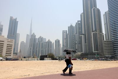 A Dubai resident takes shade on a hot May day in Business Bay. Chris Whiteoak / The National