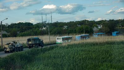 Russian militrary vehicles escort buses carrying Ukrainian troops from the Azovstal steel plant. EPA