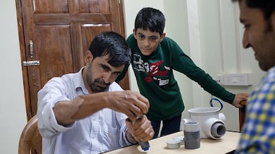 Abdul Rahim carries out exercises crucial to his hands' rehabilitation, as his son watches. Harsha Vadlamani for The National