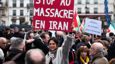 A protester holds a placard reading ''Stop the massacres in Iran'' during an anti-government rally in support of the Iranian people in Paris. Getty Images